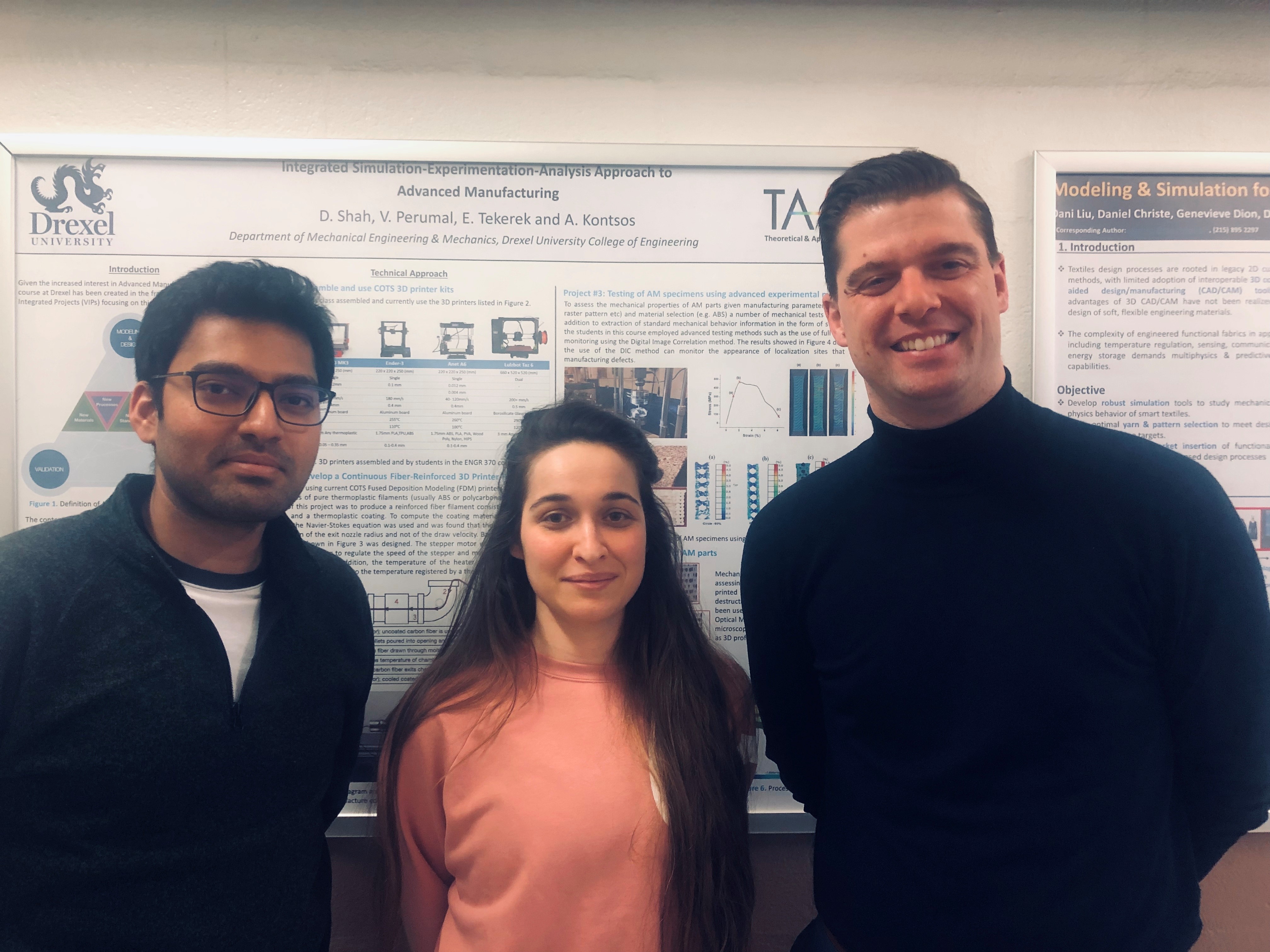 Two men and one woman stand in front of an engineering poster